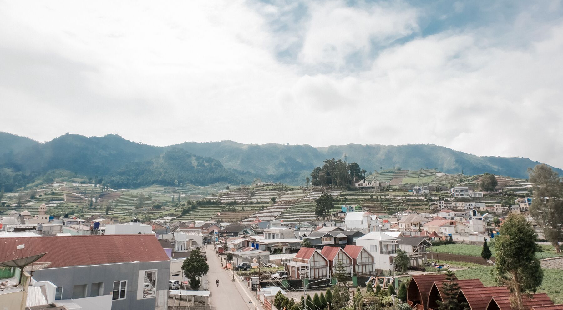 A town with terraced fields and a mosque in the background.