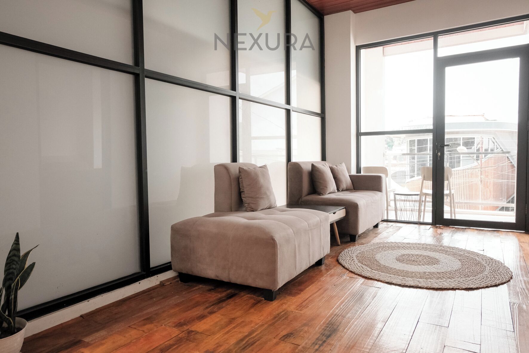 A modern living room with a sectional sofa, a round rug, and a large sliding glass door leading to a balcony.