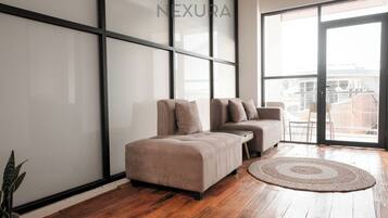 A modern living room with a sectional sofa, a round rug, and a large sliding glass door leading to a balcony.