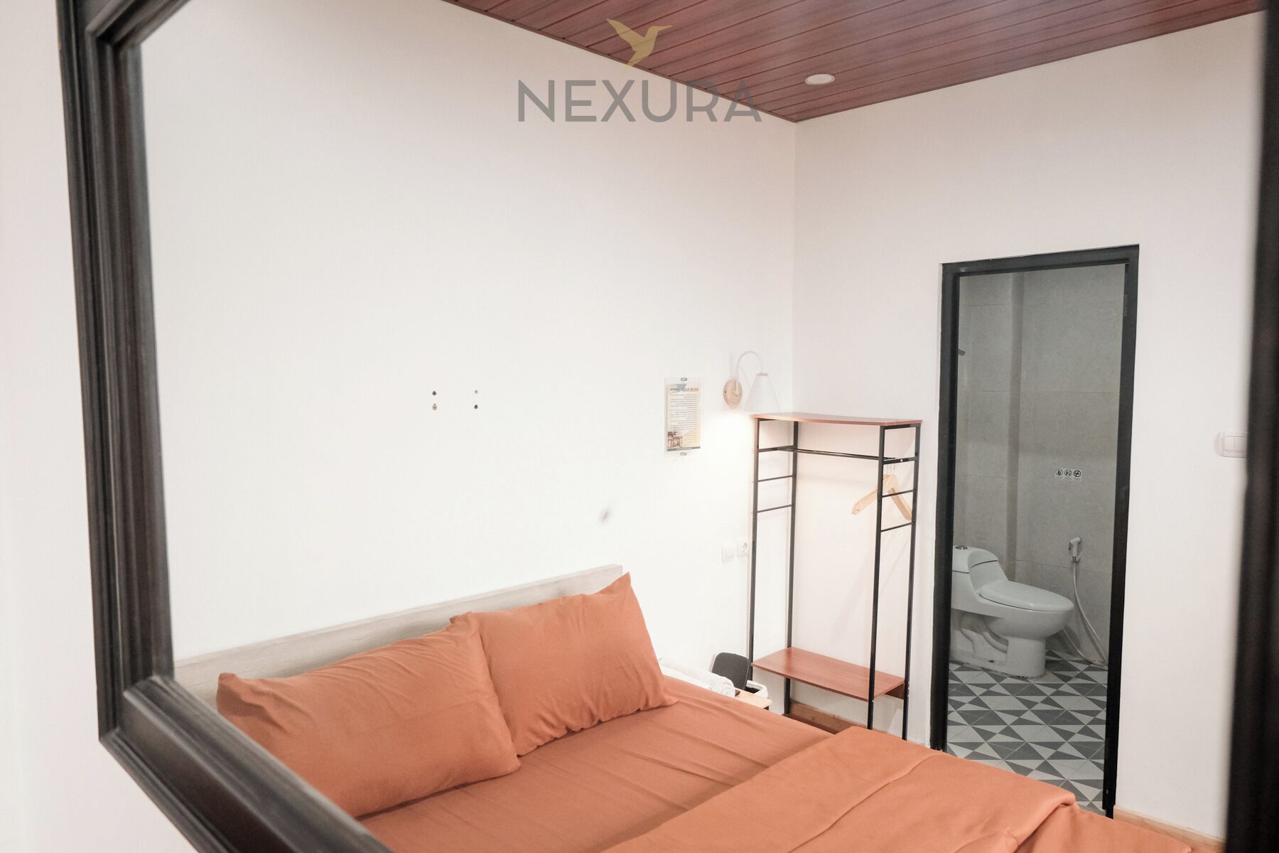 Ein Schlafzimmer mit einem Bett, einem kleinen Schreibtisch, einem Spiegel und einer Tür zu einem Badezimmer.