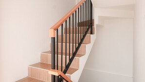A staircase with wooden steps and black metal railings. - Limaran Syariah Nexura Collection (Dieng Kulon)