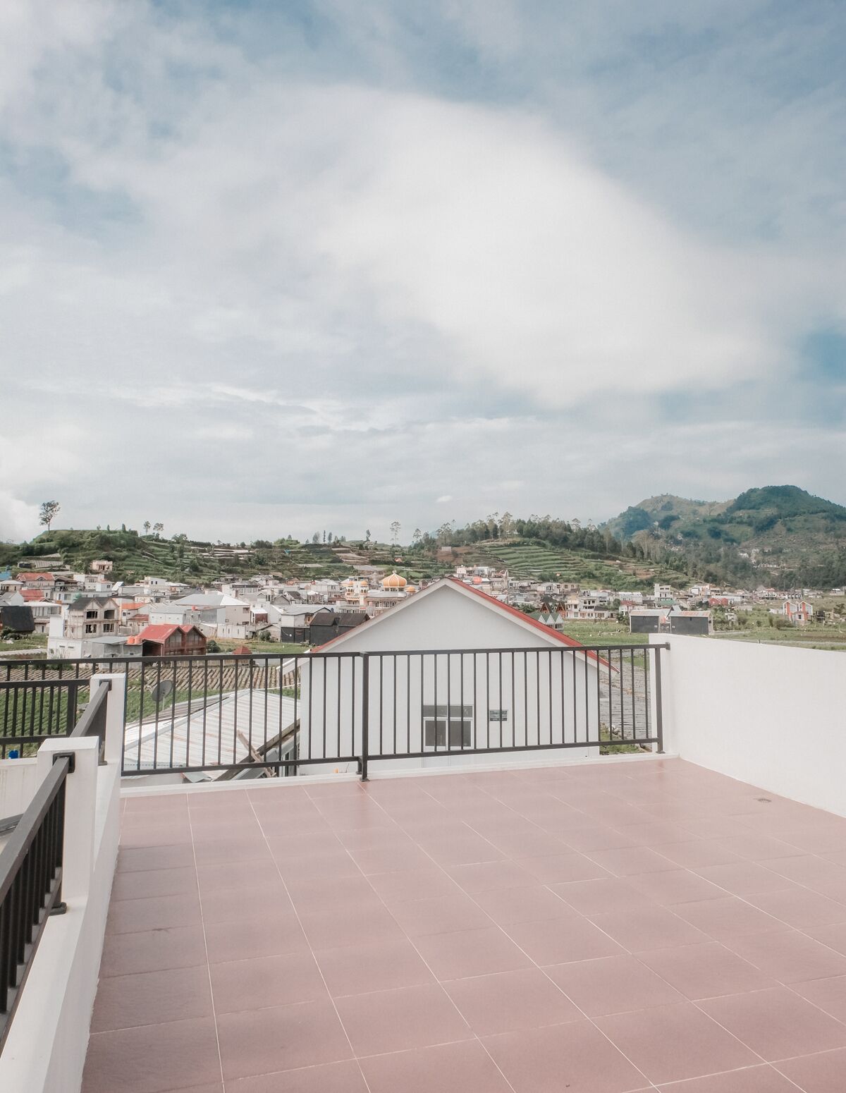 A rooftop terrace with a view of a residential area and hills in the distance.