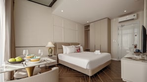 Una habitación de hotel con una cama, un escritorio con un frutero, una silla y un televisor.