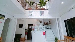 A spacious lobby with a staircase, potted plants, and a chandelier. - Luna Oslob Travellers Inn (Oslob)