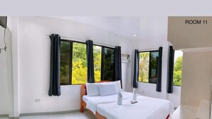 A bedroom with a bed, a window with curtains, and a sign indicating "ROOM 11". - Luna Oslob Travellers Inn (Oslob)