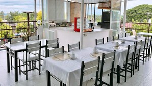 A restaurant with outdoor seating, a bar area, and a view of the surrounding landscape. - Luna Oslob Travellers Inn (Oslob)