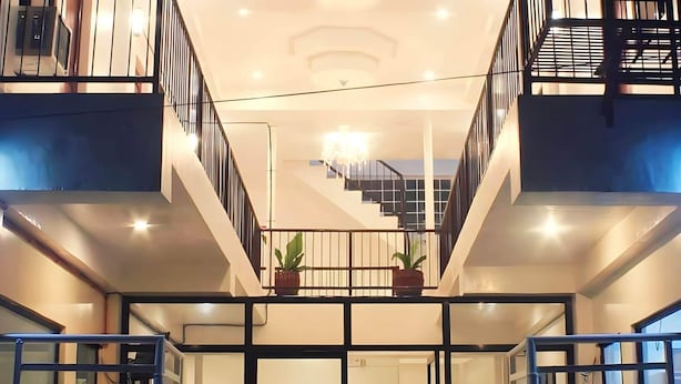 A modern building with a central atrium, glass doors, and potted plants. - Luna Oslob Travellers Inn (Oslob)