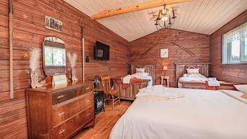 A rustic wooden room with a large bed, a dresser, a chair, and a fireplace.