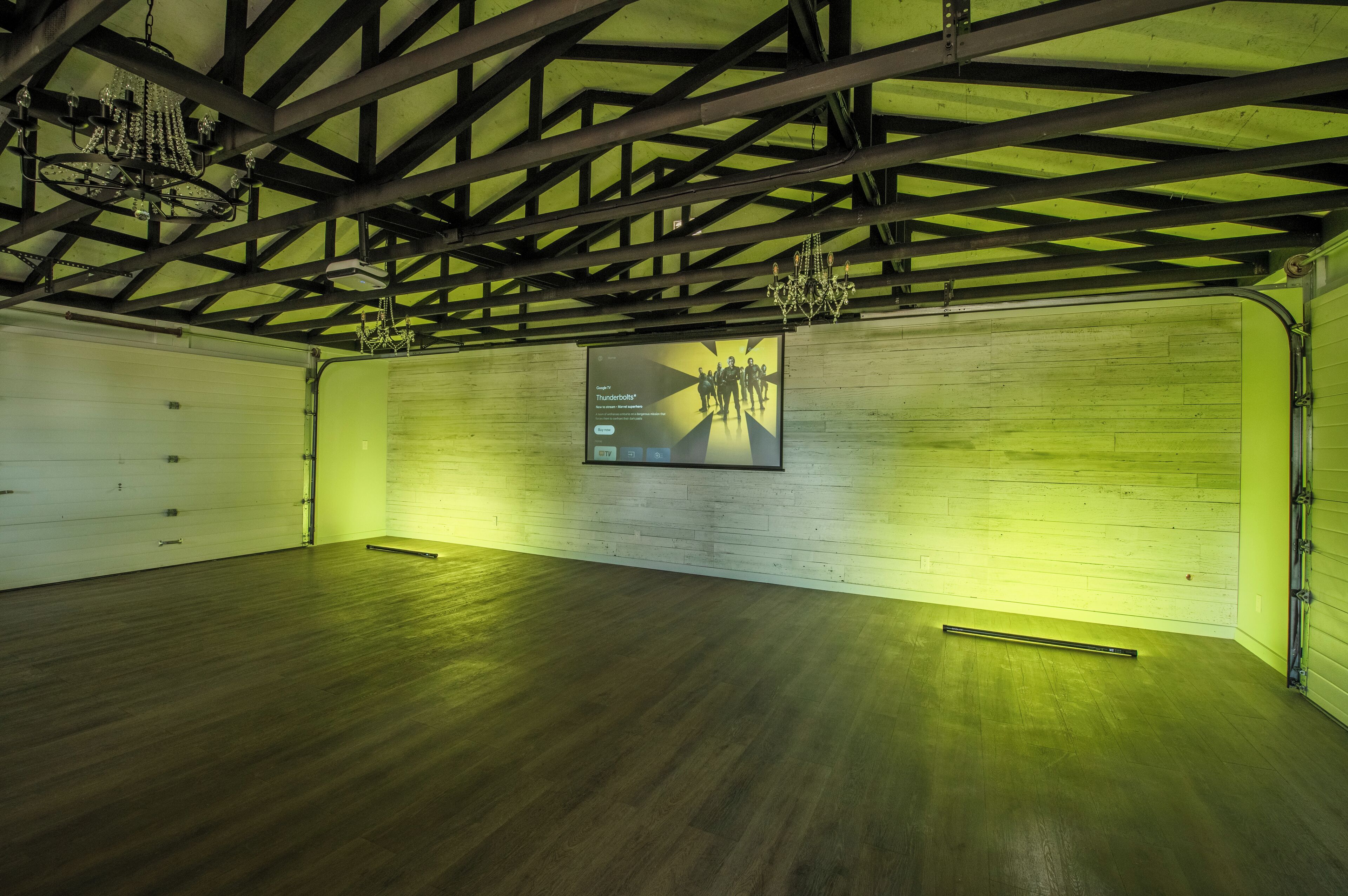 A spacious room with a high ceiling, exposed beams, and a wooden floor.