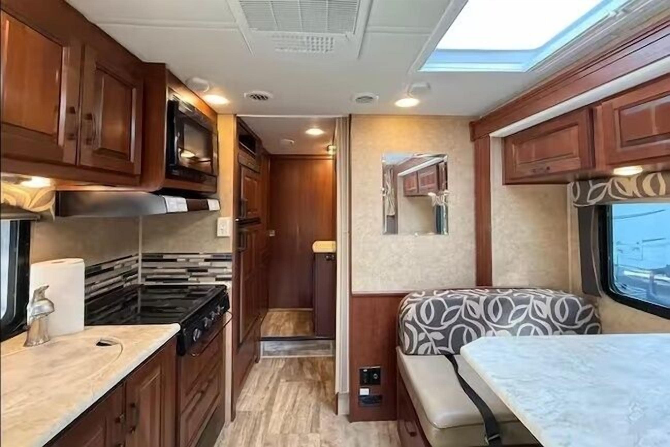 Una cocina compacta para autocaravana con armarios de madera, estufa y microondas.