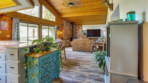 L’intérieur chaleureux d’un chalet avec un plafond en bois, un téléviseur, un canapé et un coin repas.