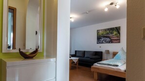 A room with a bed, a sofa, a table, a mirror, and a painting on the wall. - Apartment 'Marita Sigg' with Private Terrace, Shared Garden and Wi-Fi (Rust)