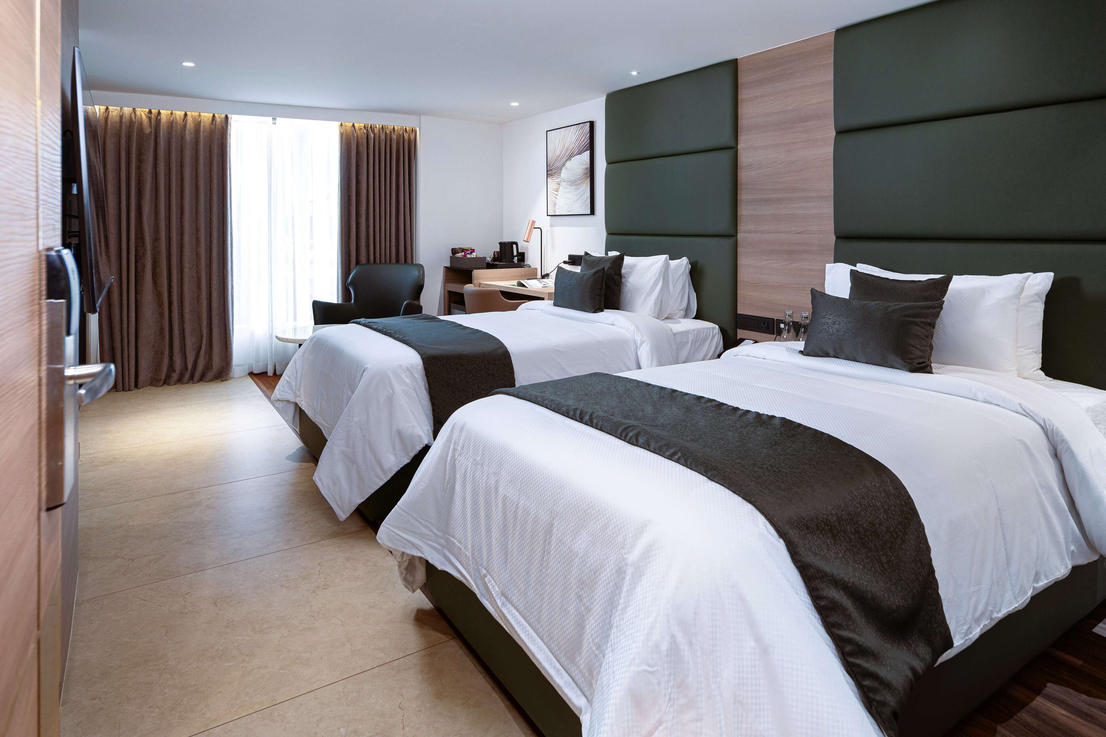 Una habitación de hotel con dos camas, un escritorio, una silla y un televisor.