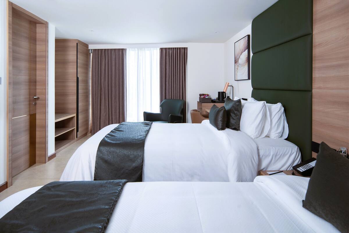 Ein Hotelzimmer mit zwei Betten, einem Schreibtisch, einem Stuhl und einem Kleiderschrank.
