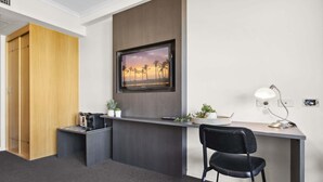 A hotel room with a desk, a chair, a TV mounted on the wall, a lamp, and a small plant on the desk. - Mantra Parramatta Studio with Pool Access (Parramatta)