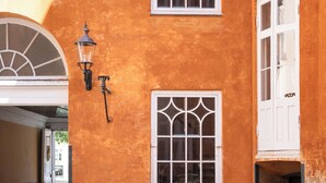 A building with a distinctive orange facade, white-framed windows, and a traditional street lamp. - Former Dukes Residence - 4 bedrooms - 2 bathroms (København)