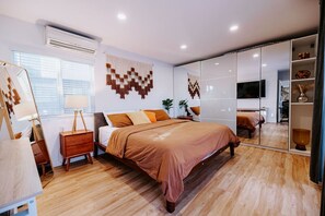 A modern bedroom with a large bed, bedside tables, a mirror, and a TV.
