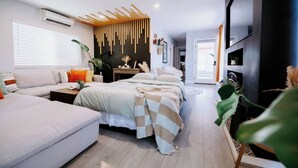 A modern bedroom with a sofa, two beds, a wooden slat wall, and a TV. - Central SD• Luxury Home+Casita, Pool•Hot tub•BBQ•Sleeps10 (La Mesa)