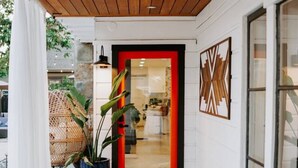 A modern entrance with a wooden ceiling, a red-framed door, and a potted plant. - Central SD• Luxury Home+Casita, Pool•Hot tub•BBQ•Sleeps10 (La Mesa)