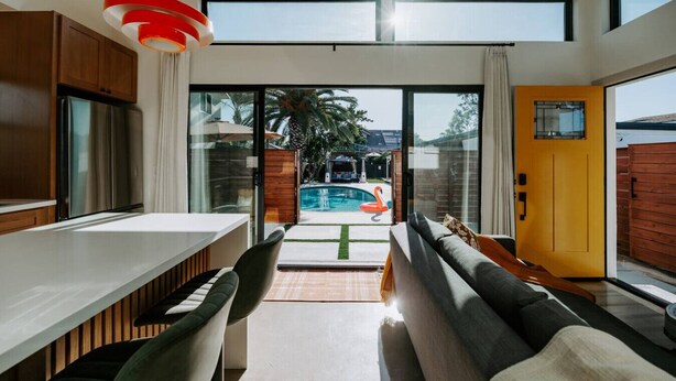 A modern kitchen with a large island, a dining area with a sofa, and a view of a swimming pool. - Central SD• Luxury Home+Casita, Pool•Hot tub•BBQ•Sleeps10 (La Mesa)