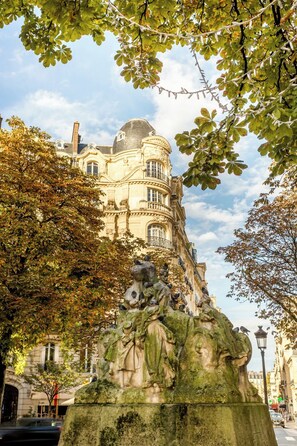 A historic building with ornate architecture, a prominent dome, and a statue of figures on a pedestal. - Merveil Luxury Suites - Cyr I-II - Terrasse (Paris)