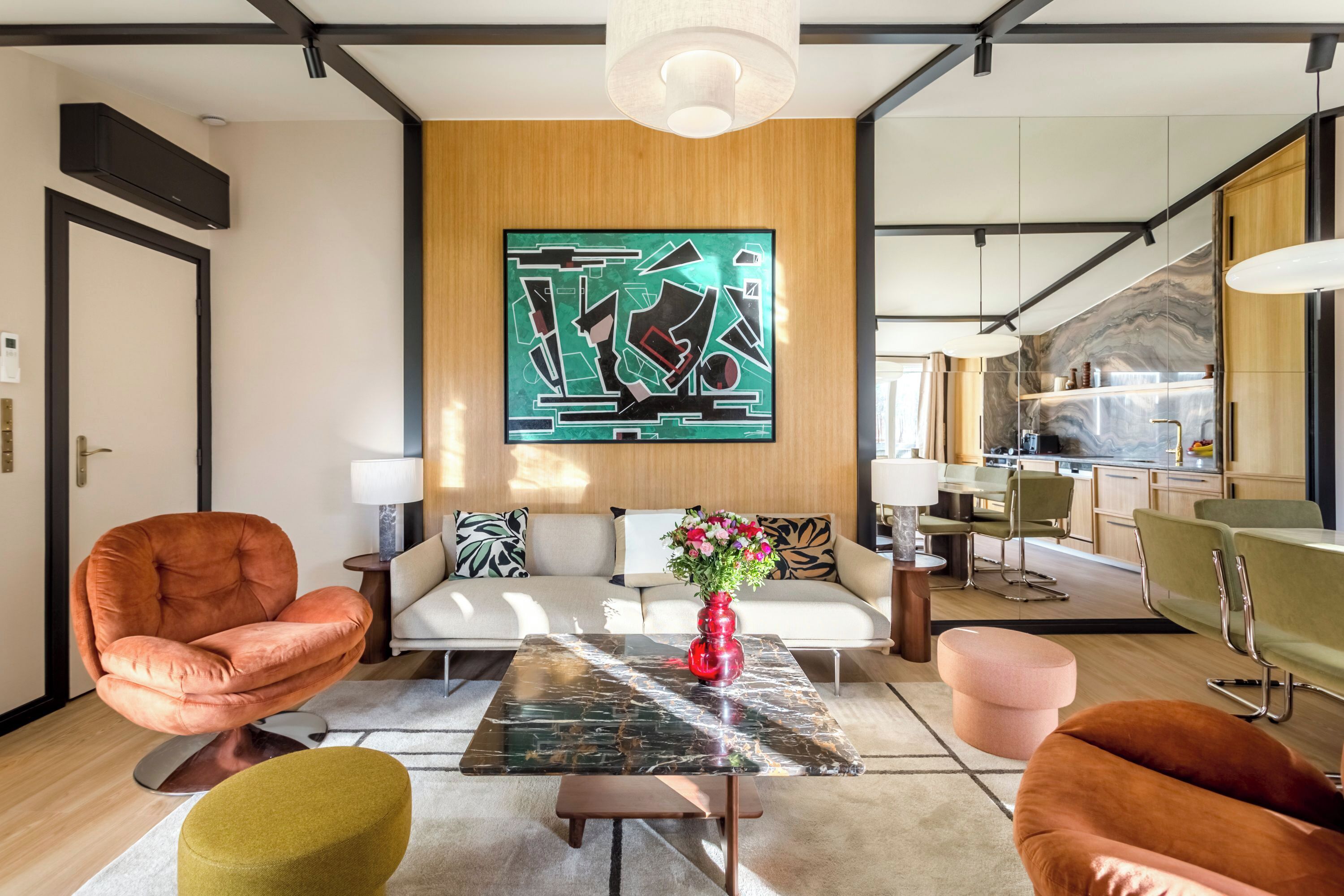 A modern living room with a sofa, armchairs, a coffee table, and a large abstract painting on the wall.