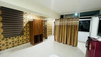 A bedroom with a bed, wardrobe, curtains, and a window.