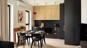 Una cocina moderna con armarios de madera, encimera negra y zona de comedor con mesa y sillas.