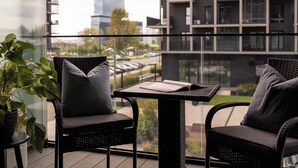 Ein Balkon mit zwei Korbstühlen, einem kleinen Tisch und einem Topfpflanzen.