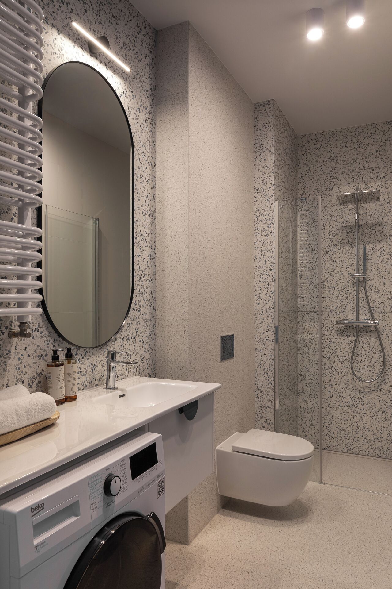 A modern bathroom with a large mirror, a sink, a toilet, and a shower.