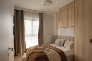 Un dormitorio moderno con una cama, un armario y un ventanal con cortinas.