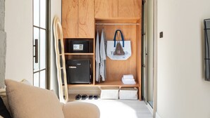 A compact room with a wooden wardrobe, a small black safe, a towel rack, and a pair of shoes. - Chunnchay Bed&Restaurant (Mae Wang)