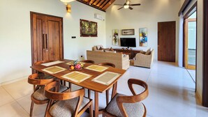 Amplia sala de estar con una mesa de comedor de madera, cuatro sillas, un sofá y un televisor.