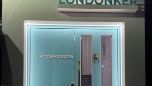 En dörr till ett boende, målad i en nyans av turkos, med en skylt ovanför som visar texten "LONDONKER".