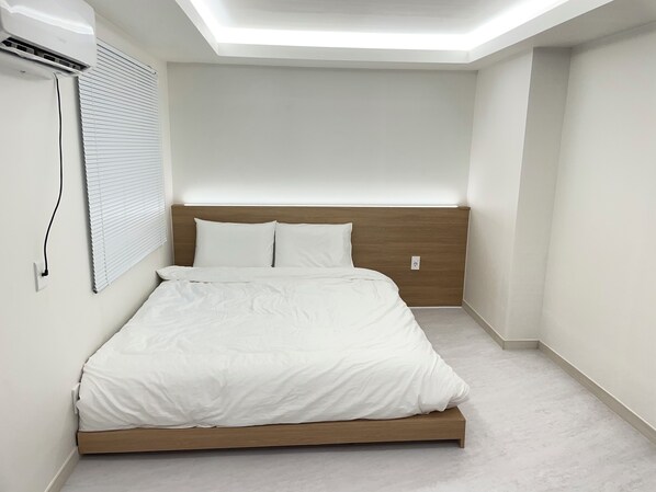 A neatly made bed with white bedding in a room with a sloped ceiling and a built-in headboard. - Londonker (Busan)