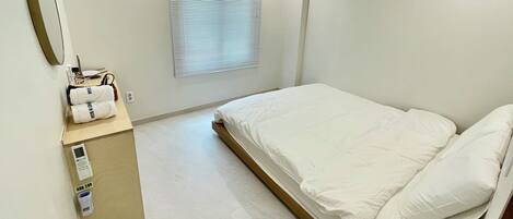 Et moderne hotelværelse med en seng, et lille skrivebord med en computer og et vindue med persienner.