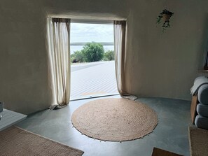 Una habitación con un ventanal grande, un tapiz tejido y vistas a una carretera y vegetación.