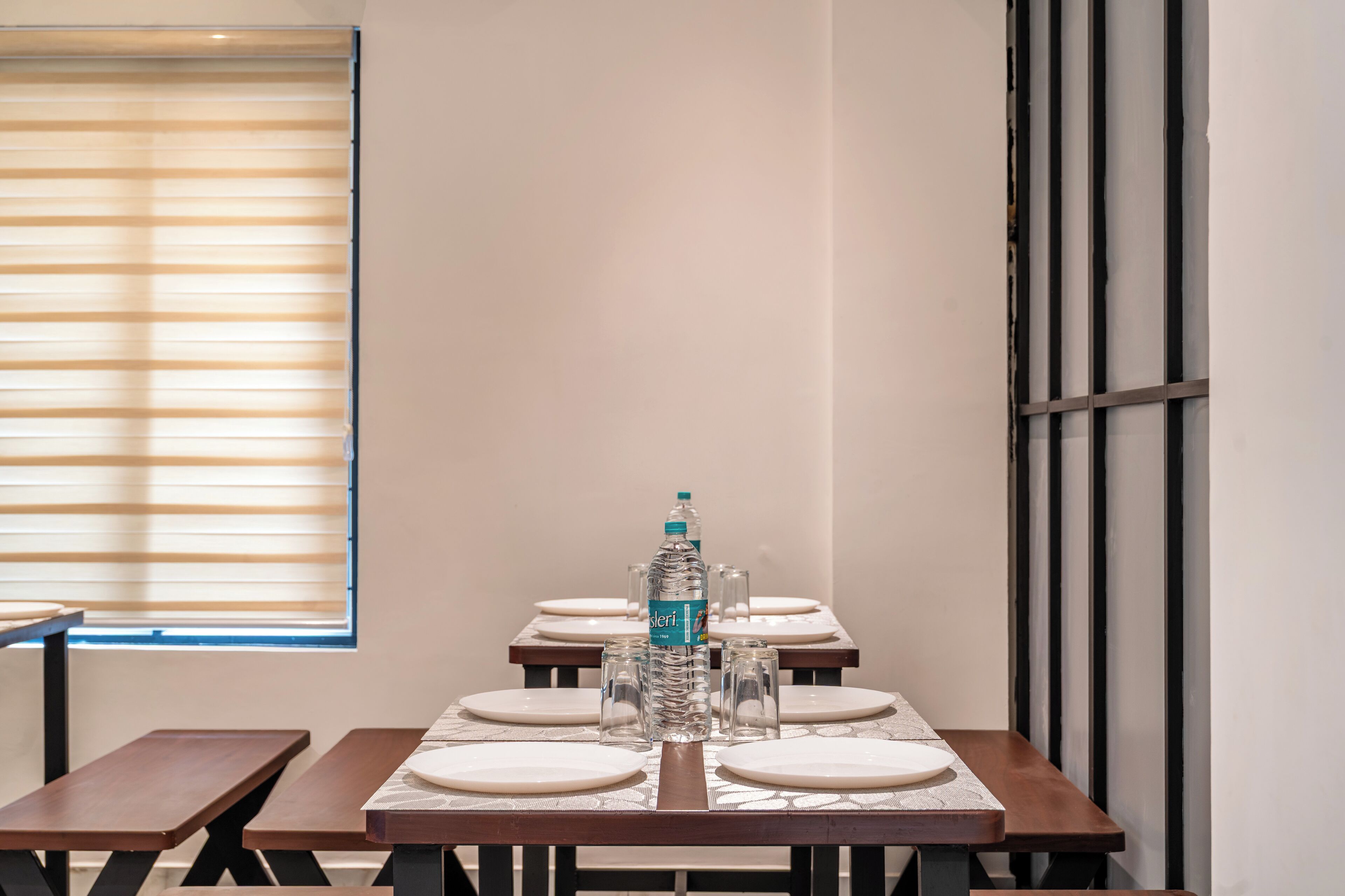 Un comedor con una mesa dispuesta para cuatro personas, una botella de agua y dos vasos sobre la mesa.