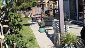 A covered patio area with a pergola, potted plants, and a wooden fence. - 4-bedroom house in an amazing neighborhood with AC, WiFi. Relax and unwind. (Imperial)