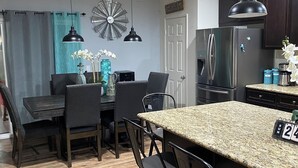 A modern kitchen with dark cabinetry, a stainless steel refrigerator, and a granite countertop. - 4-bedroom house in an amazing neighborhood with AC, WiFi. Relax and unwind. (Imperial)