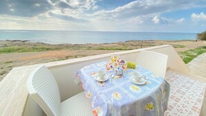 A table set outdoors with a view of the sea, a beach, and a rocky shoreline. - Beautiful home with panoramic sea view (borders state property) (Marina di Mancaversa)