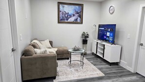 Una sala de estar con un sofá, una mesa de centro, un televisor y un cuadro en la pared.