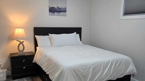 Un dormitorio con cama, mesita de noche, lámpara y un cuadro de un paisaje urbano en la pared.