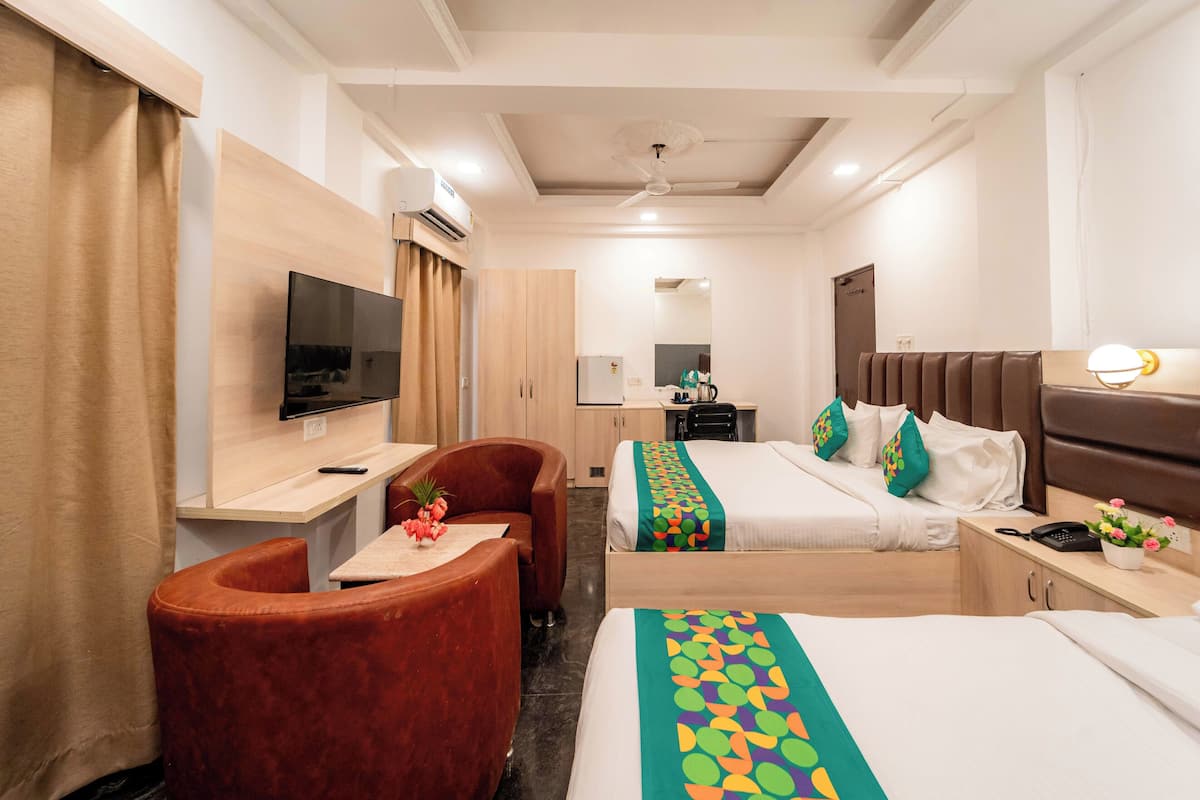 A hotel room with a bed, a desk, a chair, a TV, and a wardrobe.