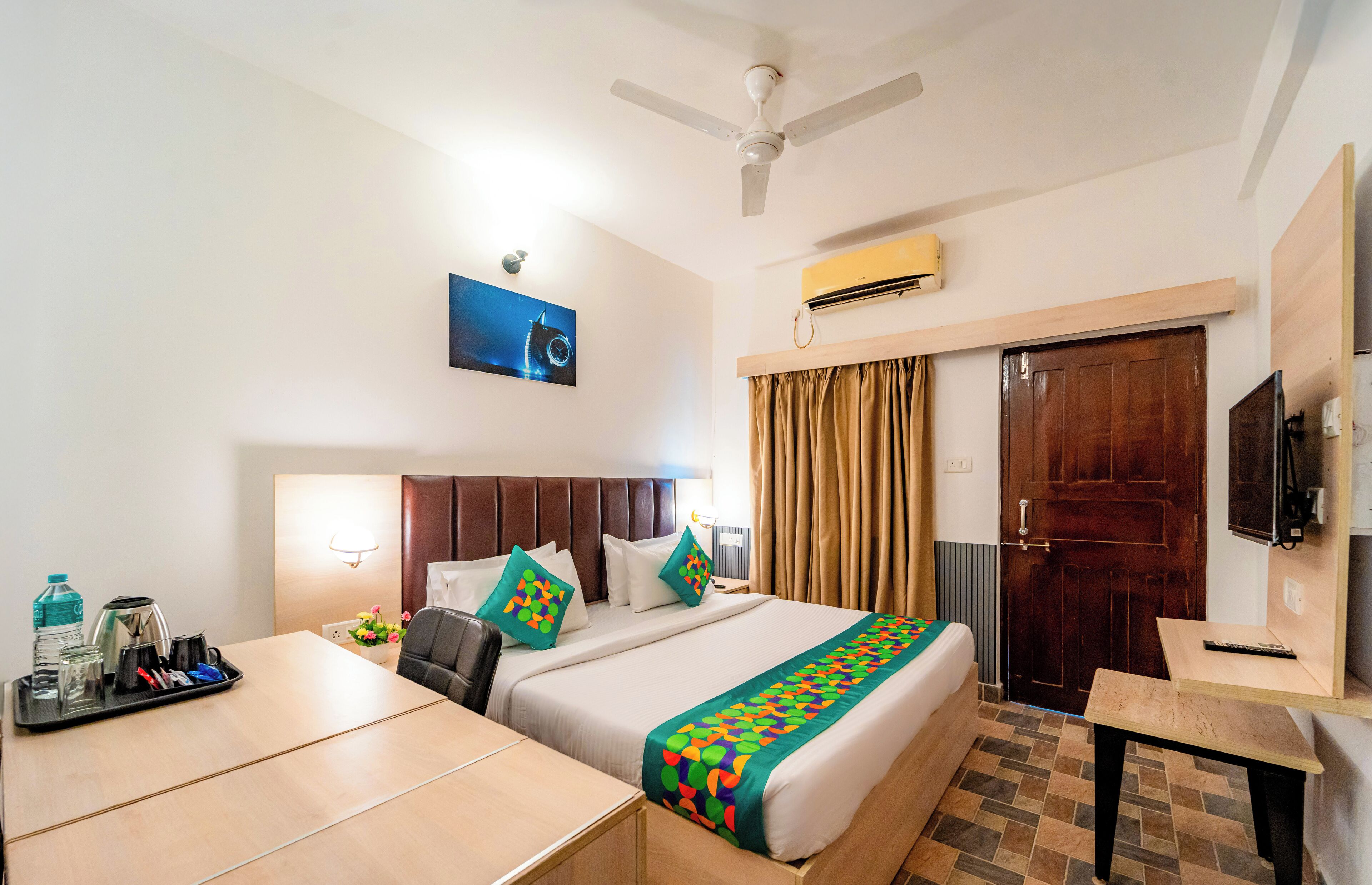 A hotel room with a bed, a desk, a chair, a TV, and a ceiling fan.
