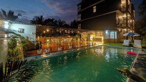 A swimming pool with a glass enclosure, surrounded by potted plants and outdoor seating. - Treebo Clarissa Resort with Swimming Pool (Saligao)
