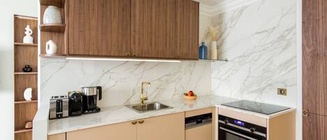 A modern kitchen with wooden cabinets, a marble backsplash, and built-in appliances including a dishwasher and oven.