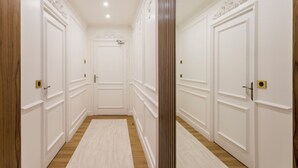 Un pasillo con puertas blancas, suelo de madera y una alfombra de tonos claros.