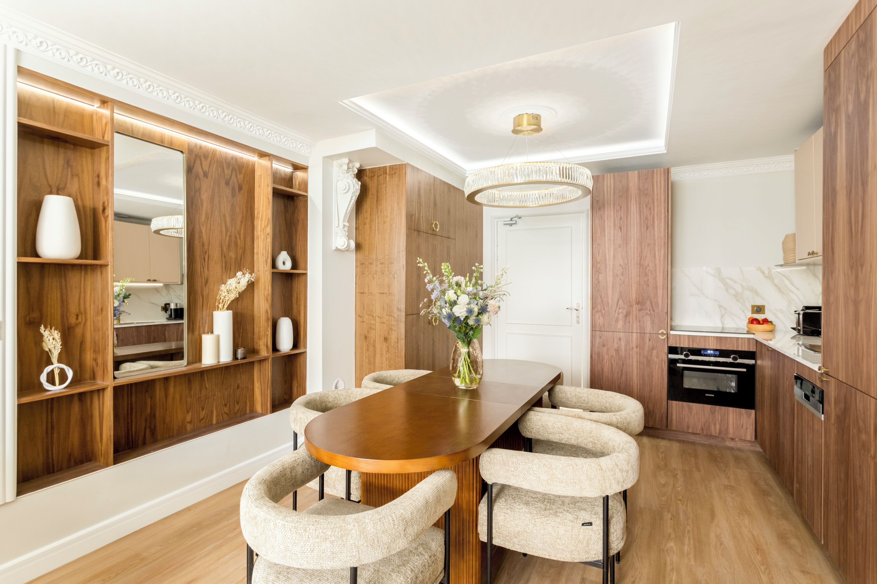 A modern kitchen with wooden cabinets, a marble countertop, and a built-in oven.