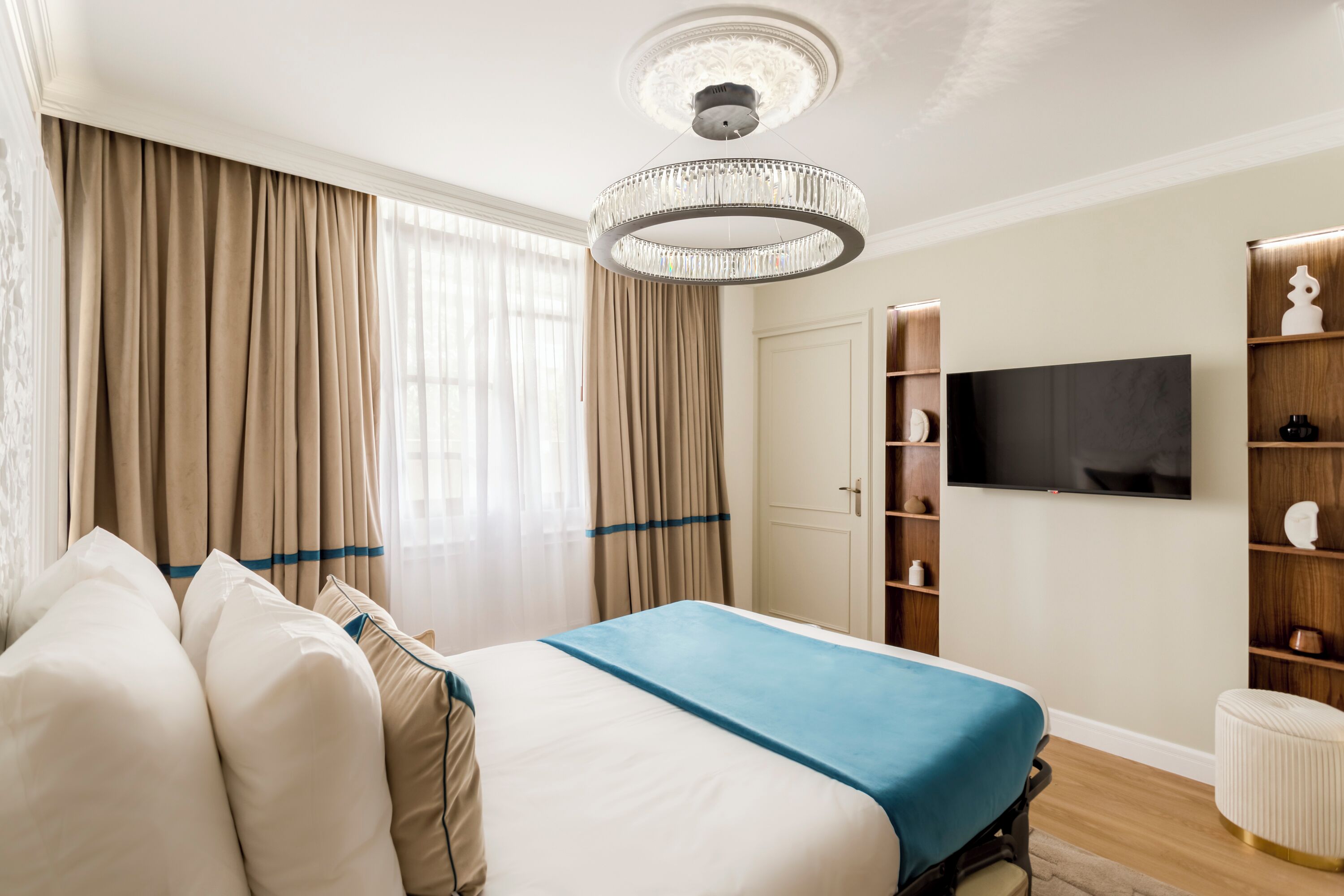 Een hotelkamer met een groot bed, een televisie, een kroonluchter en een kledingkast.